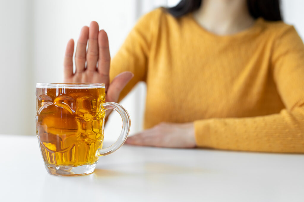 A woman holding up her hand in a stop motion next to an alcoholic drink