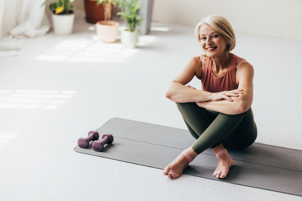 A woman remaining active sitting on a yoga mat with weights